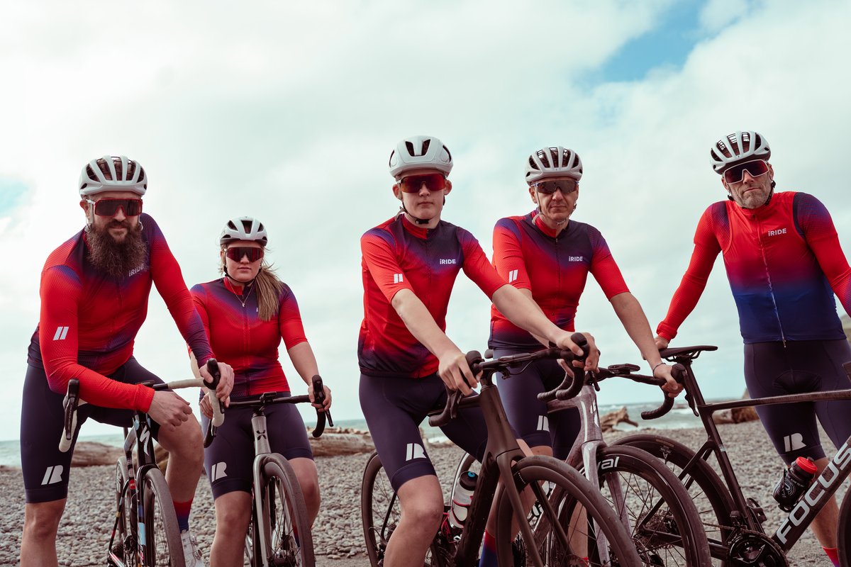 Five riders with their bikes at the beach in the new iRIDE kit.