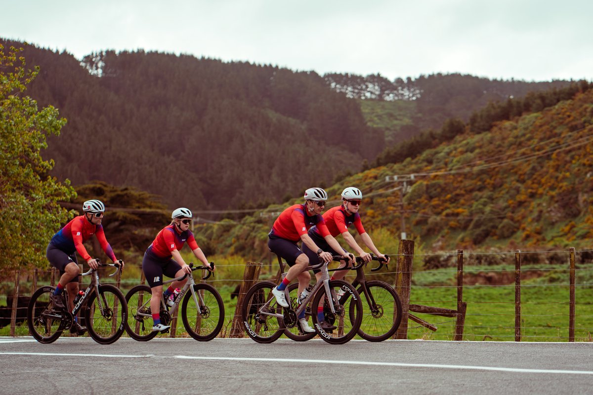 Four iRIDE riders cornering together with Mākara hills behind them.